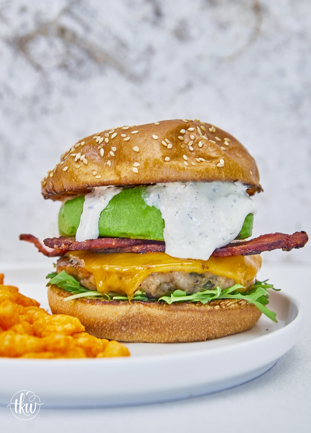 Say hello to your new favorite burger! Ground bacon & seasonings are mixed with ground chicken to make this the ultimate grilled burger! Top with melted cheese, arugula, crispy bacon, and parmesan ranch for absolute deliciousness! Ultimate Ground Chicken Bacon Ranch Burger, crack chicken burger, ground bacon burger, ranch chicken burgers, ultimate chicken burger, best chicken burger