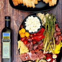 A delicious combination of Italian meats, cheeses, and grilled veggies drizzled in a zesty Italian vinaigrette. It's the perfect nibble board to gather around and takes mere minutes to put together! How to Make an Italian Antipasto Grazing Platter, antipasto platter ideas, best antipasto platter, easy antipasto, italian appetizer, antipasti, grazing board, italian charcuterie