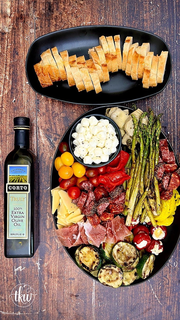 A delicious combination of Italian meats, cheeses, and grilled veggies drizzled in a zesty Italian vinaigrette. It's the perfect nibble board to gather around and takes mere minutes to put together! How to Make an Italian Antipasto Grazing Platter, antipasto platter ideas, best antipasto platter, easy antipasto, italian appetizer, antipasti, grazing board, italian charcuterie