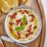 Made with rich ricotta cheese, fragrant Italian herbs, and flavorful sundried tomatoes, this dip is a symphony of flavors in every bite. Easy One Bowl Italian Herb Ricotta Dip with Sundried Tomatoes, one bowl dip, easy dip recipes, whipped ricotta, crostini toppers, bagel toppers, condiments, italian crostini, one bowl recipe