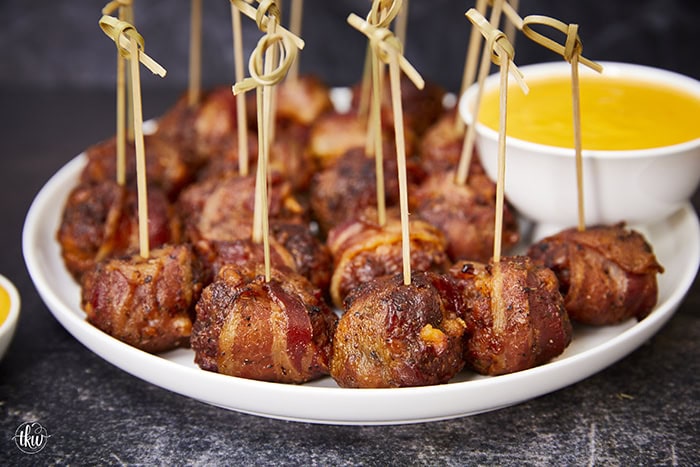 Tender, juicy meatballs oozing with cheesy goodness wrapped in seasoned bacon. It's time to fire up the smoker to make one of the best appetizers you'll ever eat! Bacon Wrapped Cheesy Big Mac Meatballs On The Smoker, cheesy meatballs, smoked meatballs, meatballs on the smoker, game day appetizers, meatballs stuffed with cheese