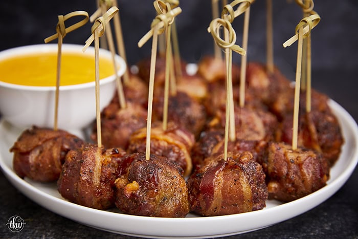 Tender, juicy meatballs oozing with cheesy goodness wrapped in seasoned bacon. It's time to fire up the smoker to make one of the best appetizers you'll ever eat! Bacon Wrapped Cheesy Big Mac Meatballs On The Smoker, cheesy meatballs, smoked meatballs, meatballs on the smoker, game day appetizers, meatballs stuffed with cheese