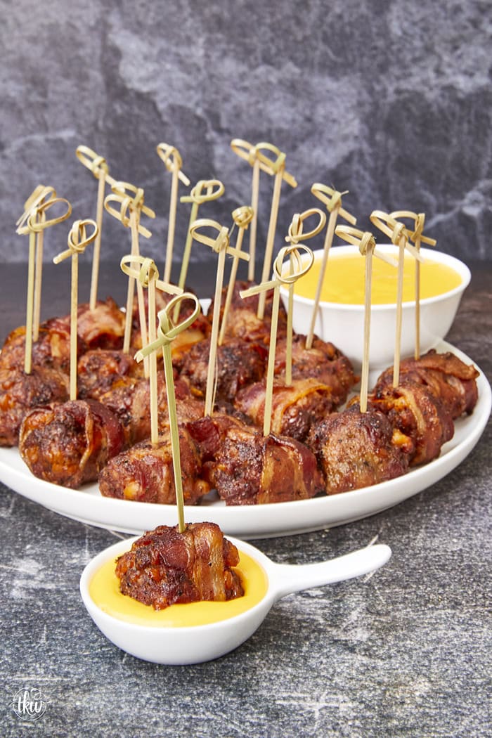 Tender, juicy meatballs oozing with cheesy goodness wrapped in seasoned bacon. It's time to fire up the smoker to make one of the best appetizers you'll ever eat! Bacon Wrapped Cheesy Big Mac Meatballs On The Smoker, cheesy meatballs, smoked meatballs, meatballs on the smoker, game day appetizers, meatballs stuffed with cheese