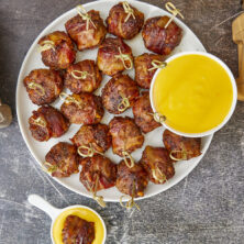 Tender, juicy meatballs oozing with cheesy goodness wrapped in seasoned bacon. It's time to fire up the smoker to make one of the best appetizers you'll ever eat! Bacon Wrapped Cheesy Big Mac Meatballs On The Smoker, cheesy meatballs, smoked meatballs, meatballs on the smoker, game day appetizers, meatballs stuffed with cheese
