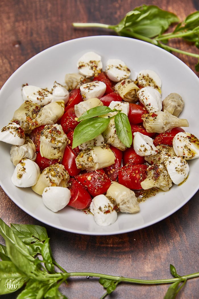 This light and refreshing Artichoke Caprese Italian Salad takes your tastebuds to Italy with each delicious bite! A delightful blend of Italian marinated tomatoes, artichoke hearts, fresh mozzarella, & basil. Simple Caprese Italian Salad with Artichokes, Italian salad, artichoke hearts, no lettuce salad, fresh mozzarella salad