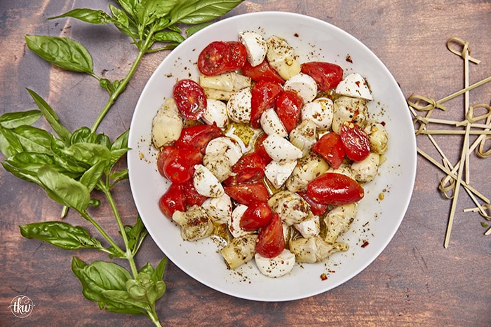 This light and refreshing Artichoke Caprese Italian Salad takes your tastebuds to Italy with each delicious bite! A delightful blend of Italian marinated tomatoes, artichoke hearts, fresh mozzarella, & basil. Simple Caprese Italian Salad with Artichokes, Italian salad, artichoke hearts, no lettuce salad, fresh mozzarella salad