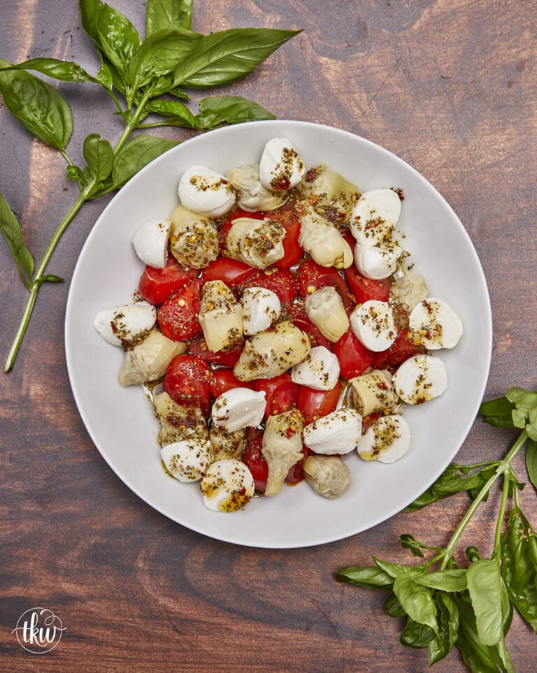 This light and refreshing Artichoke Caprese Italian Salad takes your tastebuds to Italy with each delicious bite! A delightful blend of Italian marinated tomatoes, artichoke hearts, fresh mozzarella, & basil. Simple Caprese Italian Salad with Artichokes, Italian salad, artichoke hearts, no lettuce salad, fresh mozzarella salad