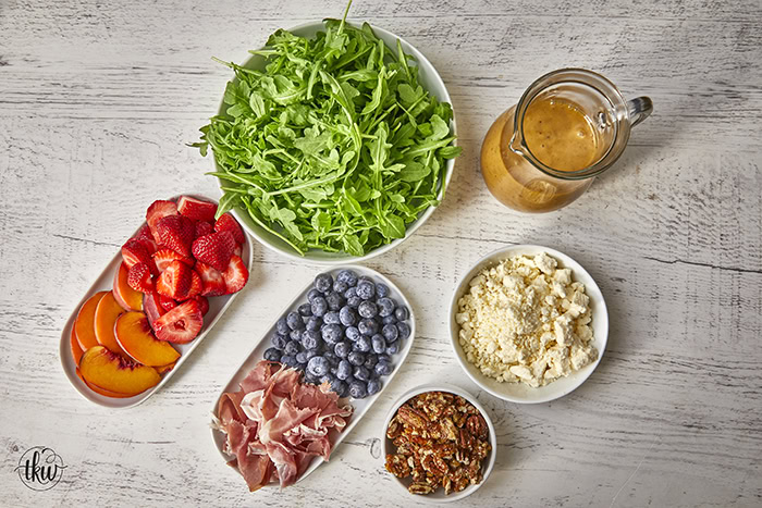 This arugula salad is bursting with freshness from feta, berries, and peaches, drizzled with a maple Dijon vinaigrette, and topped off with crunchy candied nuts. This salad is a delightful blend of savory and sweet that will tantalize your taste buds.