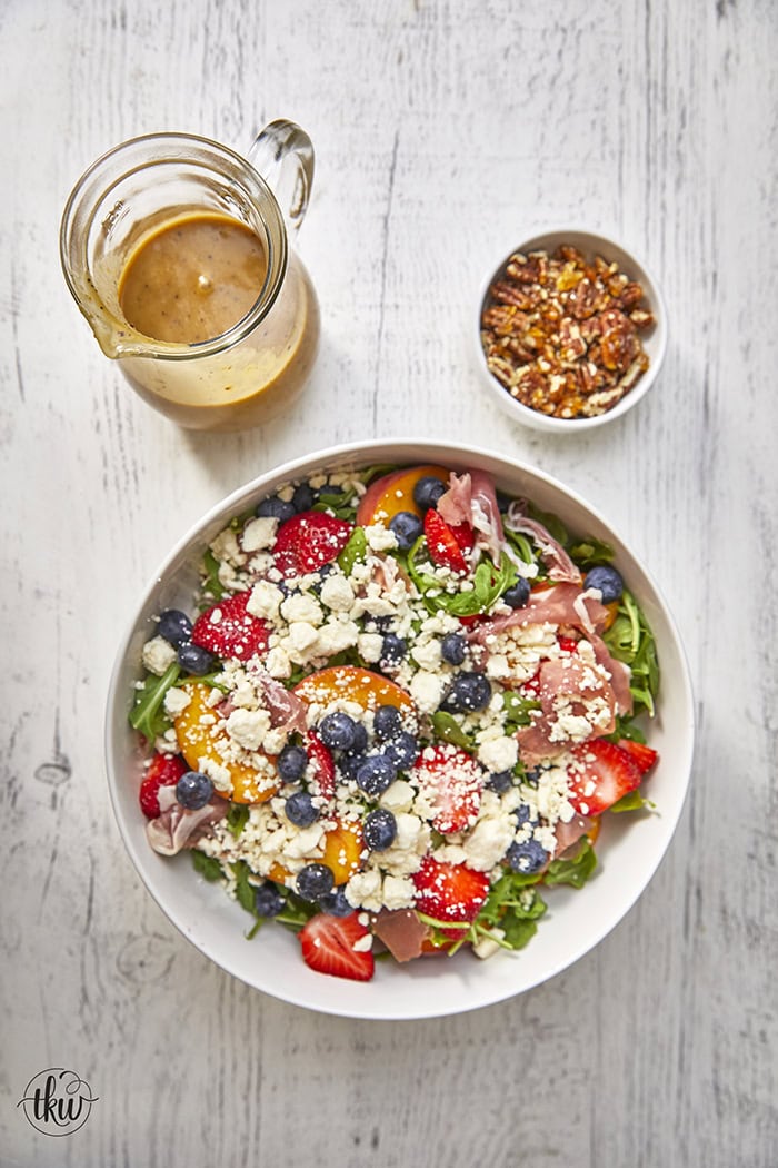 This arugula salad is bursting with freshness from feta, berries, and peaches, drizzled with a maple Dijon vinaigrette, and topped off with crunchy candied nuts. This salad is a delightful blend of savory and sweet that will tantalize your taste buds.