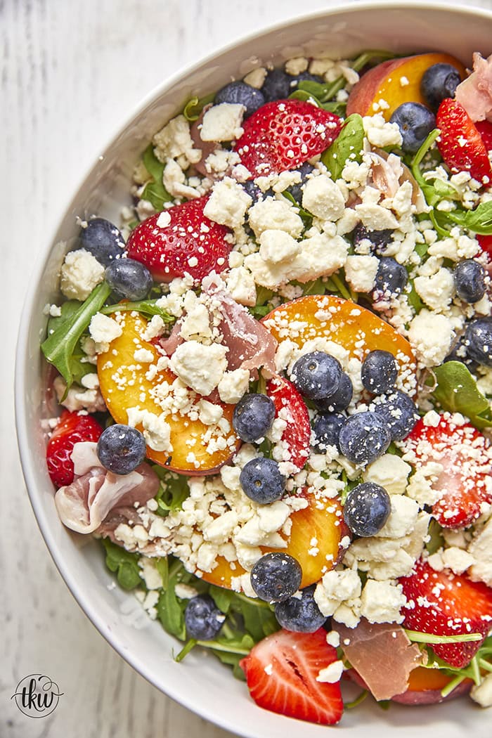 This arugula salad is bursting with freshness from feta, berries, and peaches, drizzled with a maple Dijon vinaigrette, and topped off with crunchy candied nuts. This salad is a delightful blend of savory and sweet that will tantalize your taste buds.