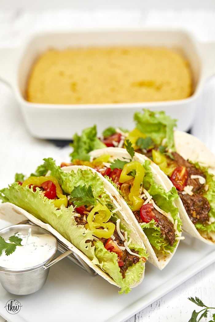 Warm flour tortillas filled with melt-in-your-mouth beef infused with bold spices, tangy banana peppers, fresh veggies, lime crema, and a sprinkling of cheese make these tacos a standout at any dinner table.