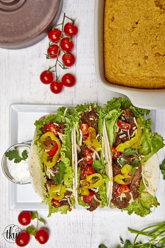 Warm flour tortillas filled with melt-in-your-mouth beef infused with bold spices, tangy banana peppers, fresh veggies, lime crema, and a sprinkling of cheese make these tacos a standout at any dinner table.