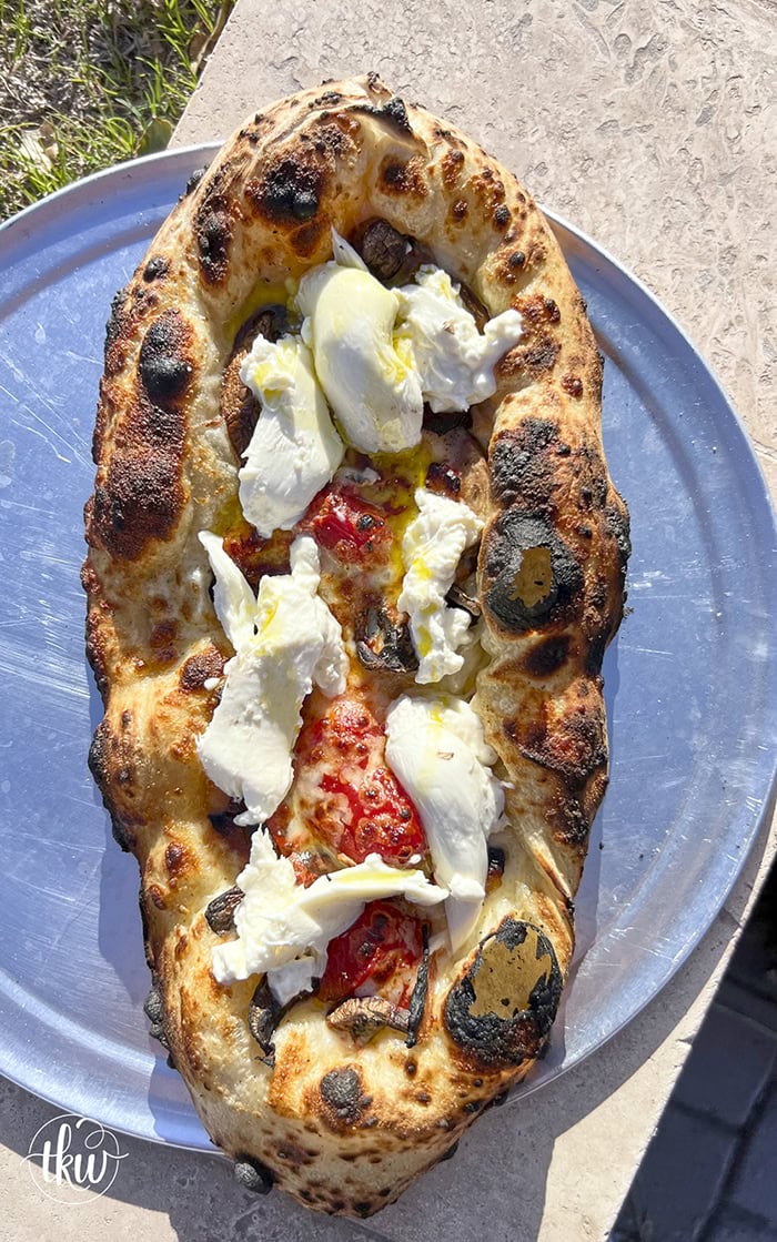 This wood-fired pizza, shaped like khachapuri, has a cheesy crust stuffed with cremini mushrooms, crispy bacon, and datterini tomatoes. It's then kissed with olive oil and finished with burrata, making it your new favorite pizza!