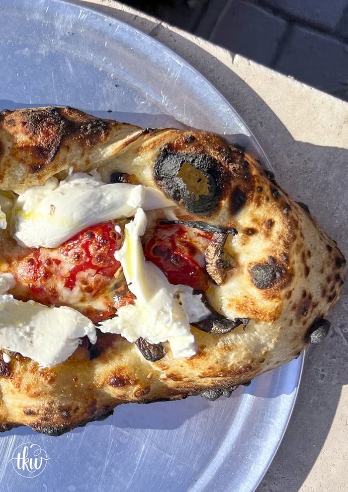 This wood-fired pizza, shaped like khachapuri, has a cheesy crust stuffed with cremini mushrooms, crispy bacon, and datterini tomatoes. It's then kissed with olive oil and finished with burrata, making it your new favorite pizza!