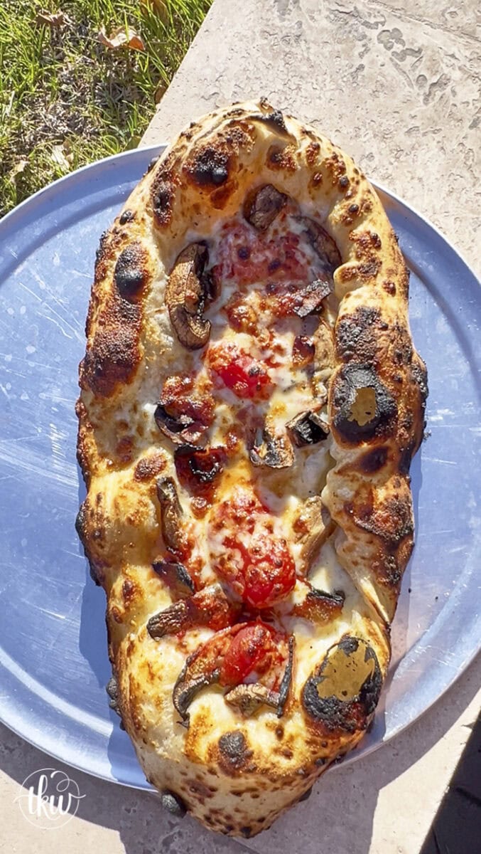 This wood-fired pizza, shaped like khachapuri, has a cheesy crust stuffed with cremini mushrooms, crispy bacon, and datterini tomatoes. It's then kissed with olive oil and finished with burrata, making it your new favorite pizza!